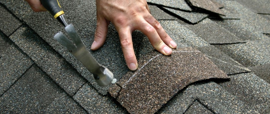 A person is cutting the shingles off of a roof.