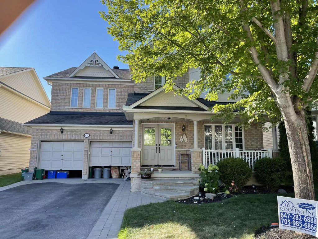 A house with two garage doors and a tree in front of it.