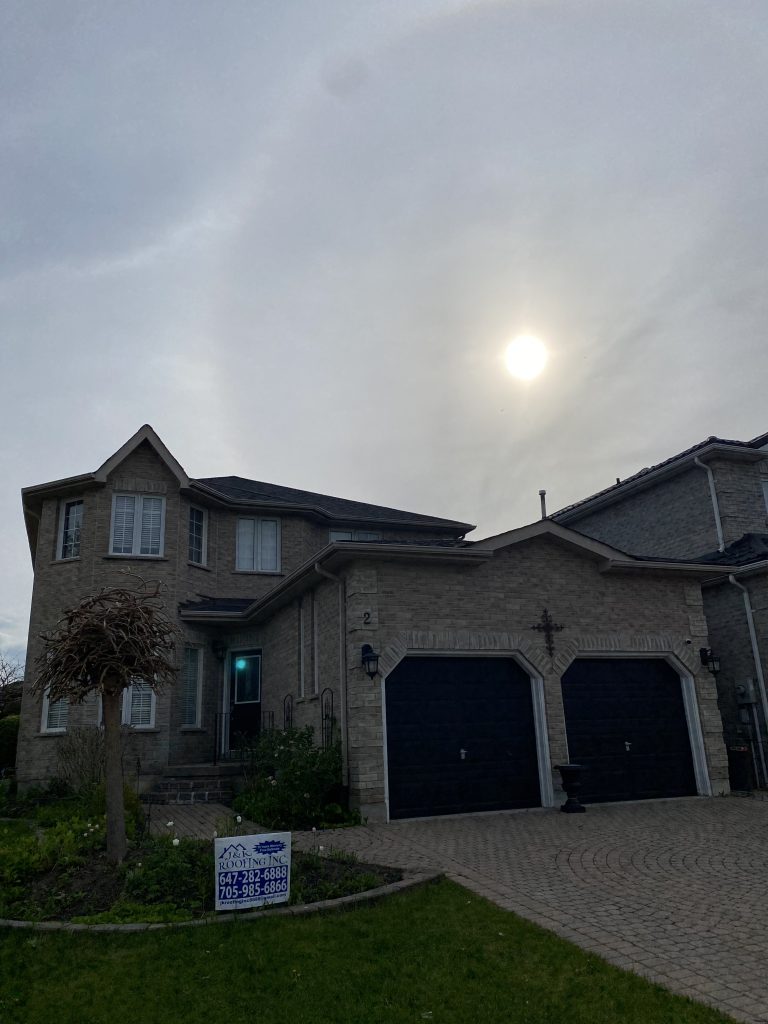 A house with two garage doors and a sun behind it.
