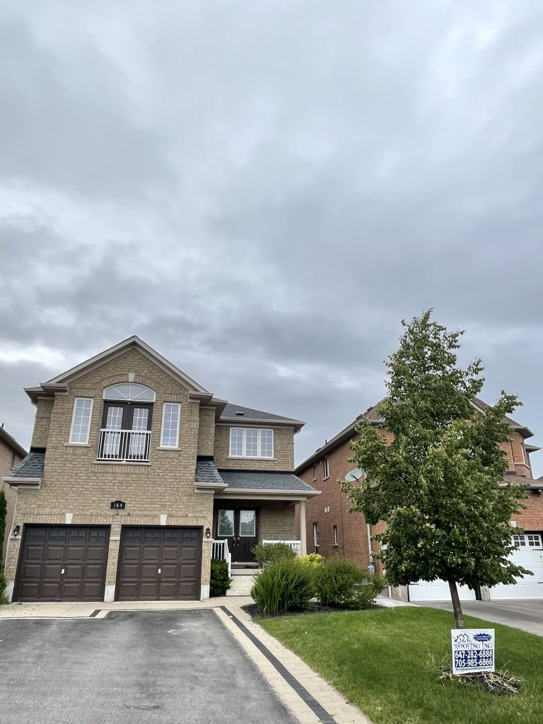 A house with two garage doors and a tree in front of it.