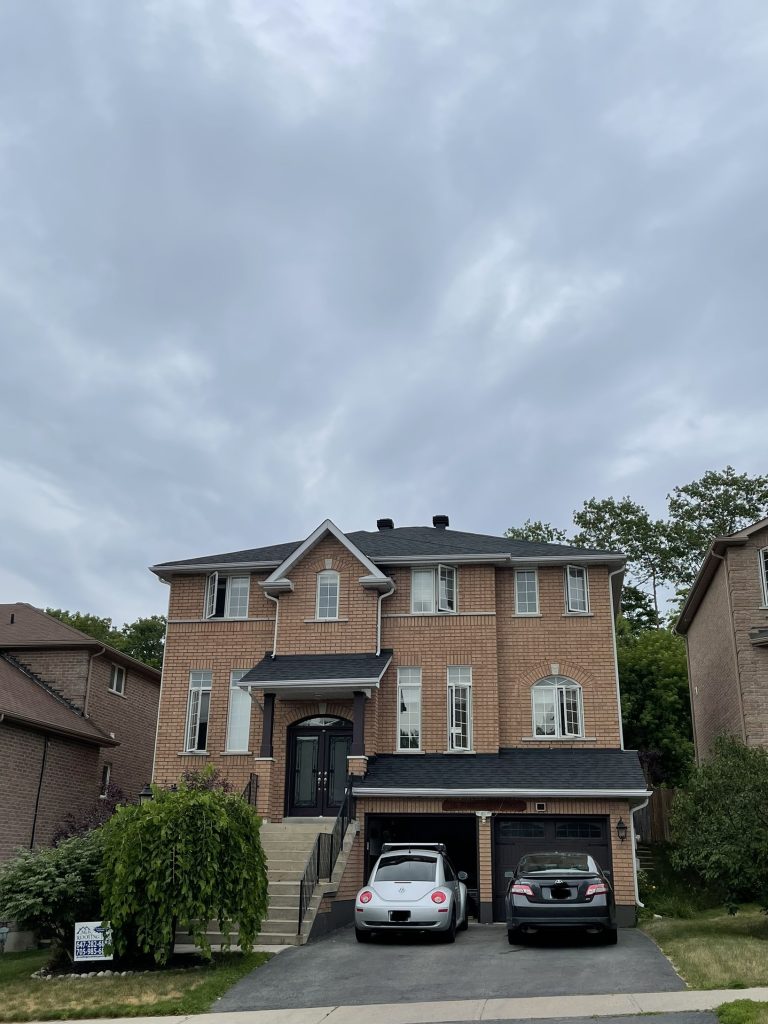 A large brick house with cars parked in front of it.