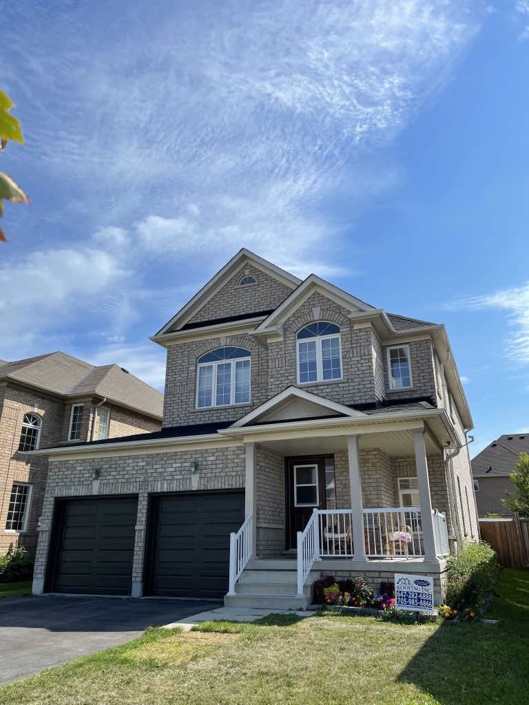 A large house with two garage doors and a blue sky.