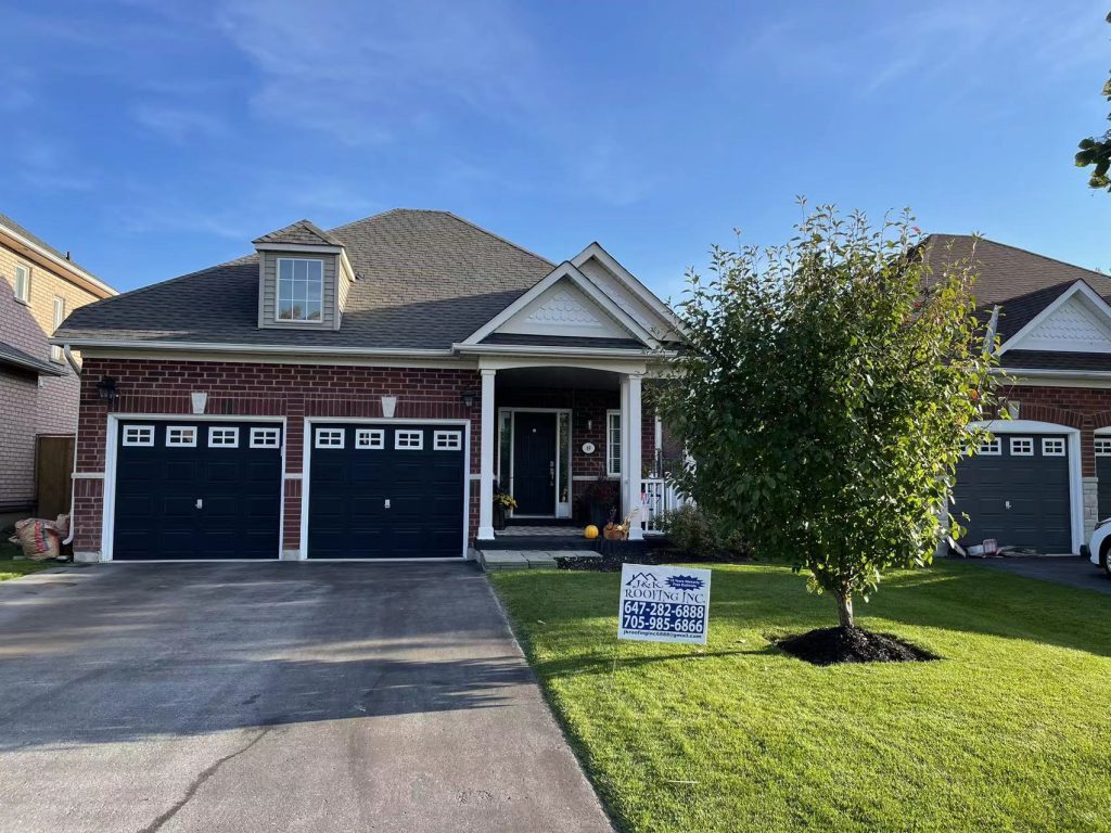A house with two garage doors and a tree in front of it.