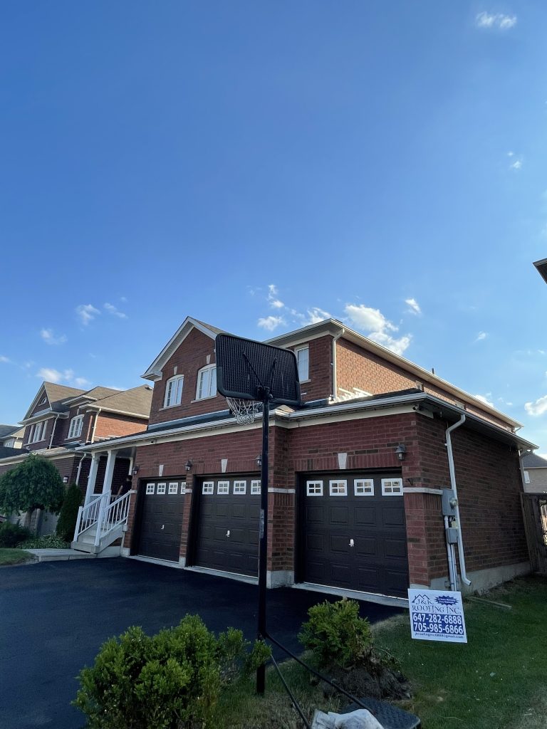 A house with two garage doors and a sign in front of it.