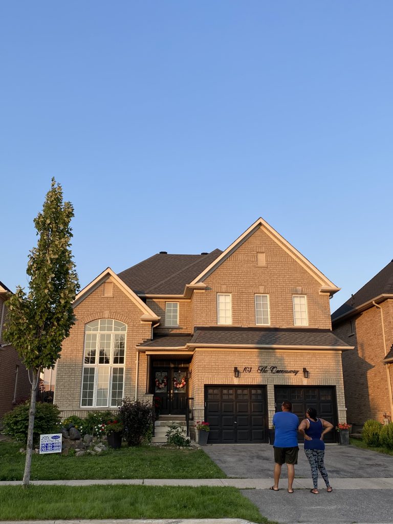 A couple of people standing in front of a house.