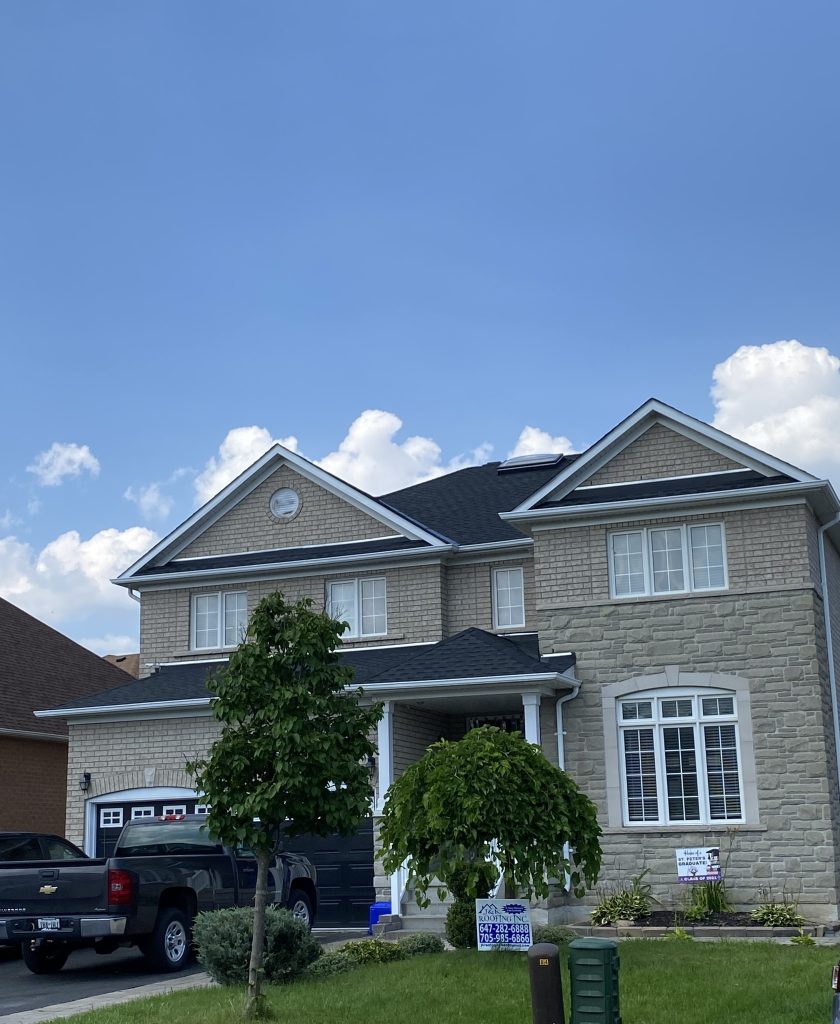 A large house with two cars parked in front of it.