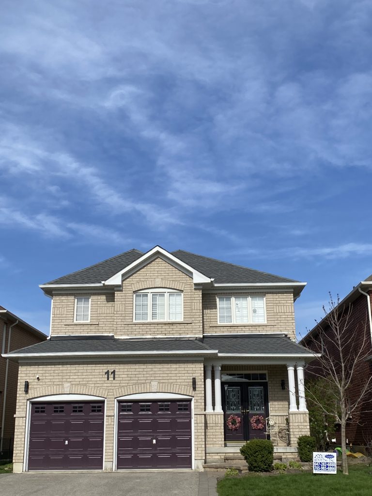 A house with two garage doors and a sky background